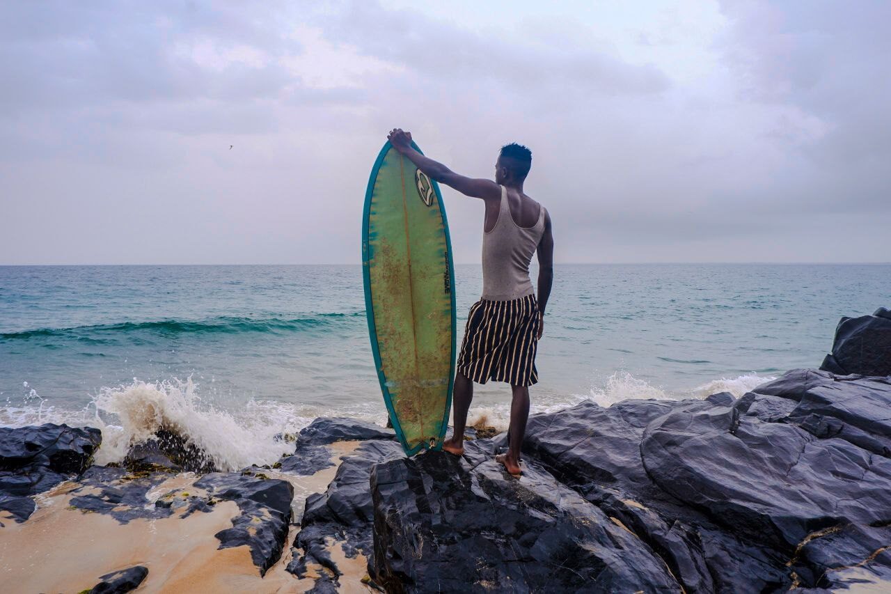 Surfer Standing on Rocks